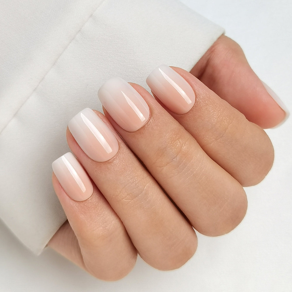 Baby Boomer Light Press On Nägel in Short Square aus einem zweiten Blickwinkel, heller Nude-Ton am Nagelbett, der weich in ein milchiges Weiß an der Spitze übergeht