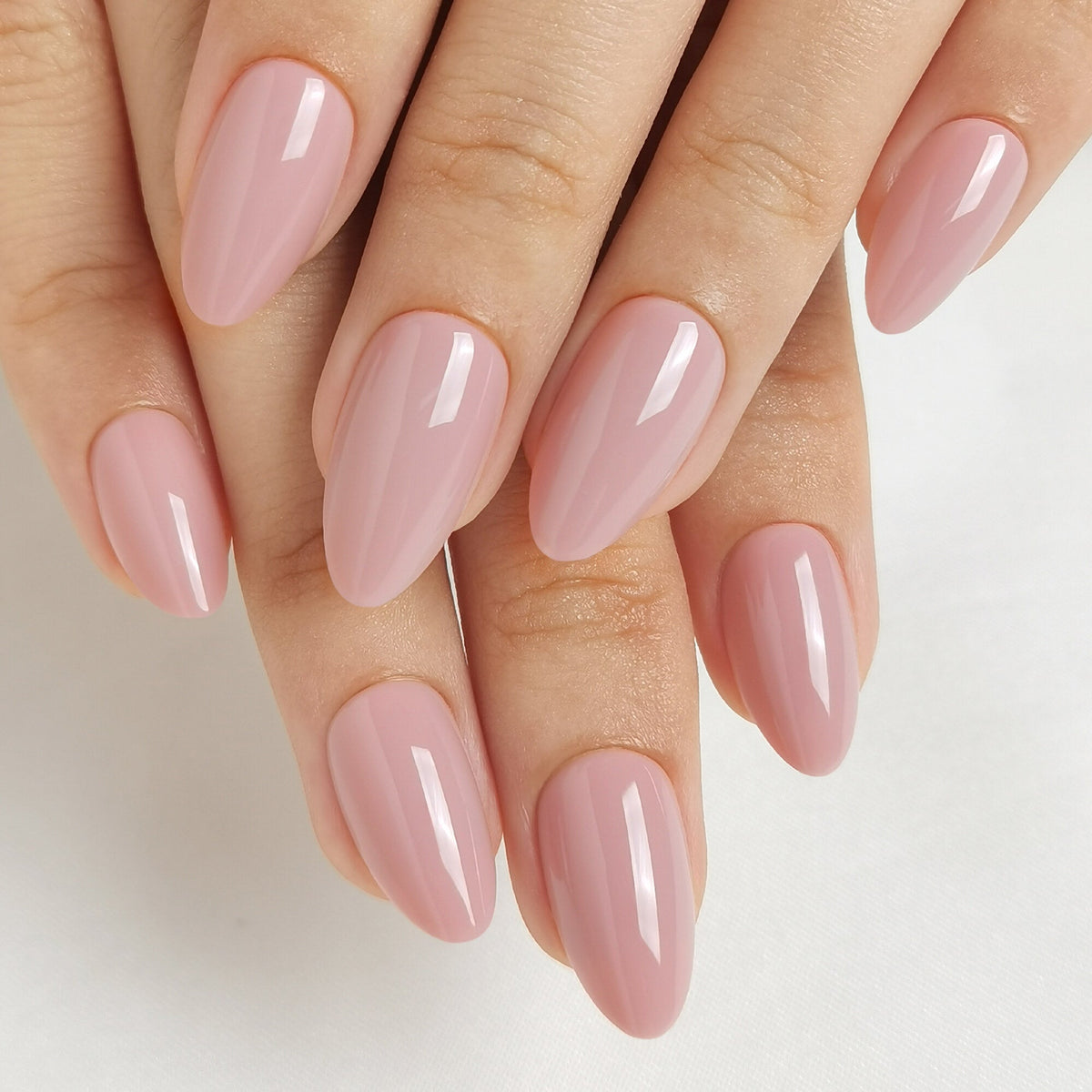 Hand mit Rosy Fusion Press On Nägeln in Short Almond, weiches, altrosa getöntes Nude mit hoher Deckkraft und glänzendem Finish