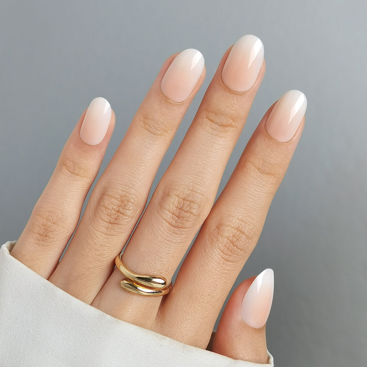 Baby Boomer Light Press On Nägel in Medium Round aus einem zweiten Blickwinkel, heller Nude-Ton am Nagelbett, der weich in ein milchiges Weiß an der Spitze übergeht