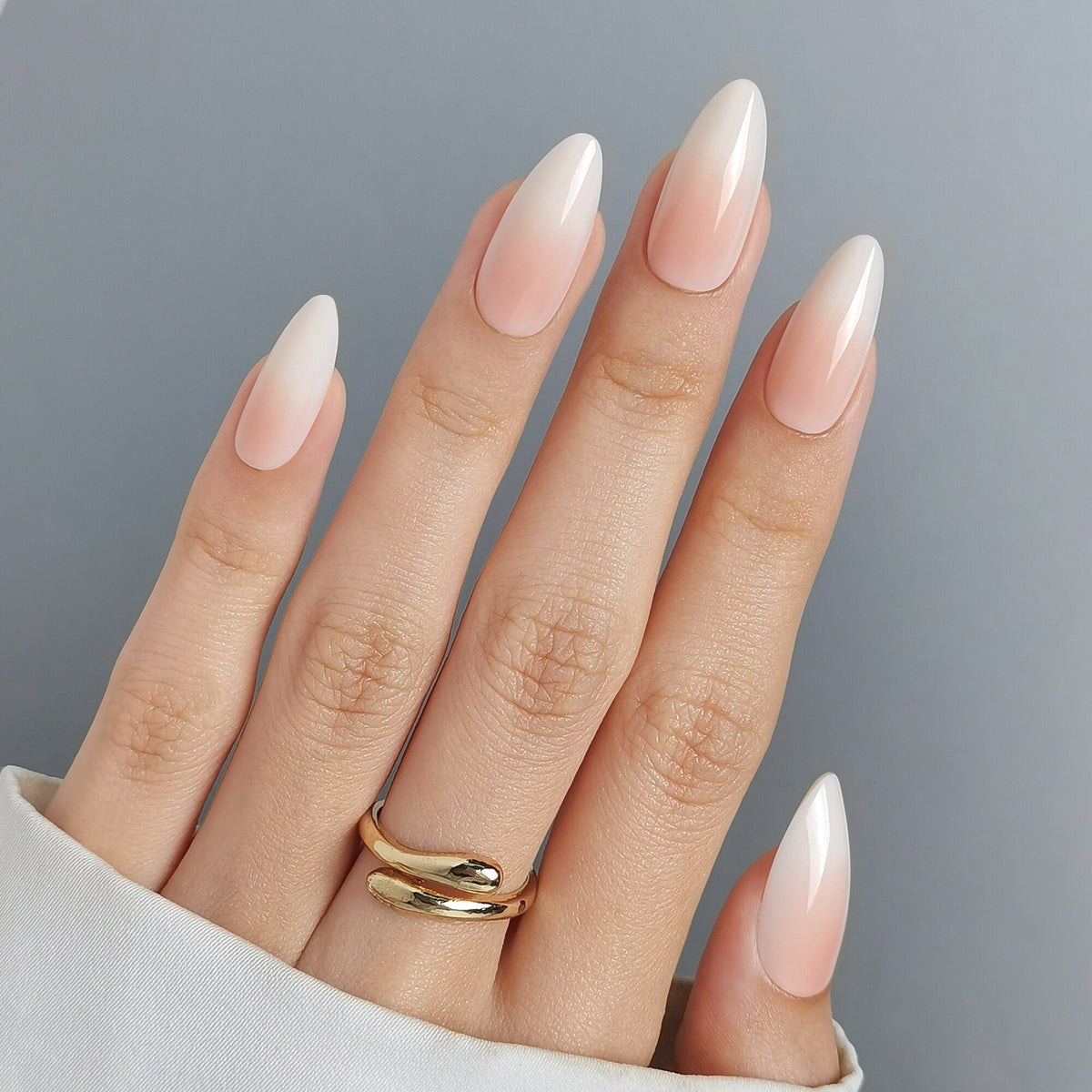 Hand mit Baby Boomer Nude Press On Nägeln in Medium Almond, zurückhaltendes Nude, das zur Nagelspitze hin heller ausläuft