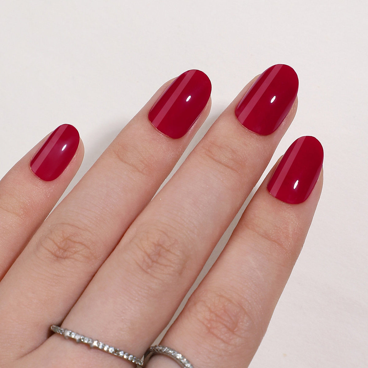 Hand mit Bonfire Red Press On Nägeln in Medium Round, sattes, tiefes Rot mit hoher Deckkraft und glänzendem Finish