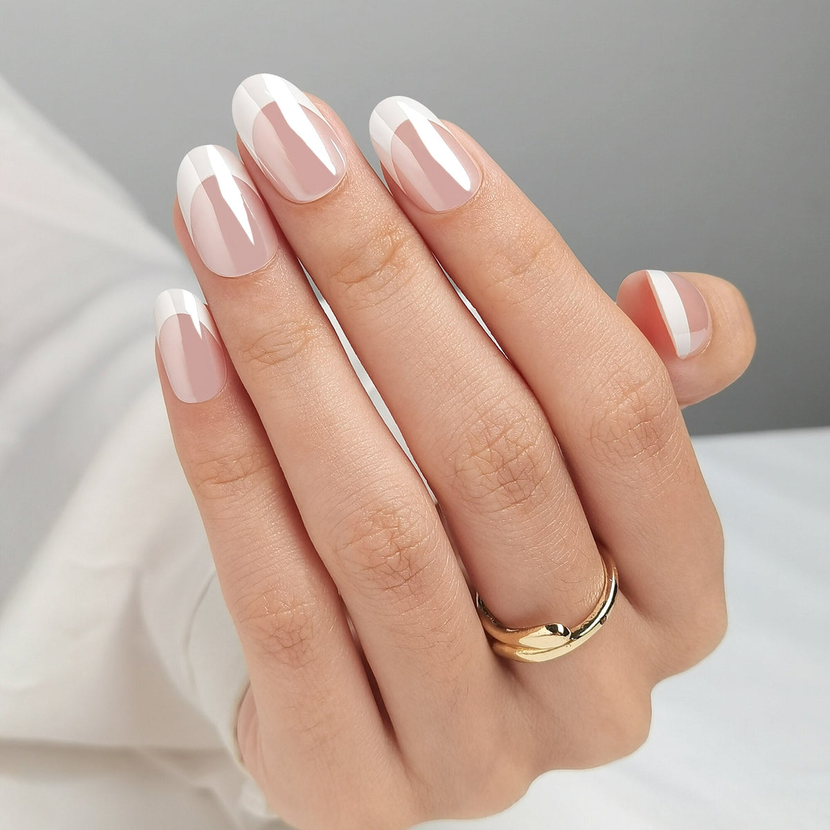 Hand mit French Nail Glow Press On Nägeln in Medium Round, nudefarbenes Nagelbett mit heller French-Spitze und einem feinen Glanzfilm darüber