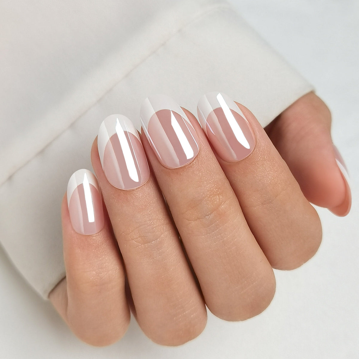 French Nail Glow Press On Nägel in Medium Round aus einem zweiten Blickwinkel, nudefarbenes Nagelbett mit heller French-Spitze und einem feinen Glanzfilm darüber