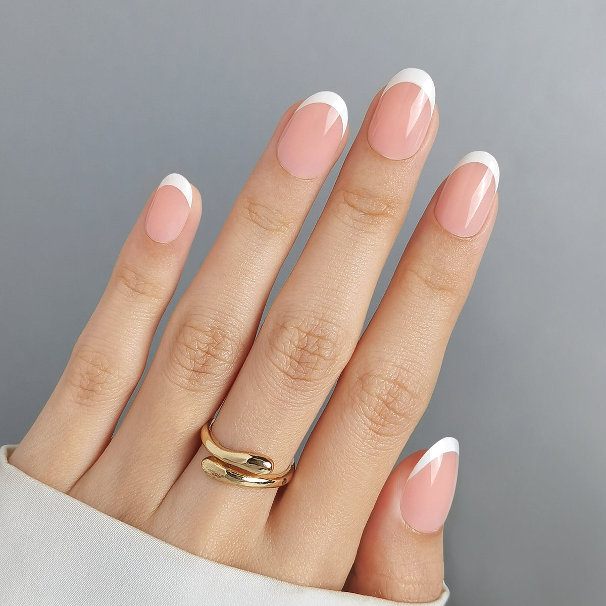 Hand mit French Nail Press On Nägeln in Medium Round, nudefarbenes Nagelbett mit klassischer weißer Spitze